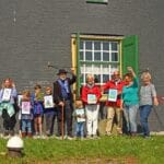 De prijswinnaars, met de wethouder Joanne Blaak, twee juryleden en de molenaar. Niet alle kinderen waren aanwezig, wel hun vertegenwoordigers (ouder, opa en oma) - Foto: Cor van der Linden