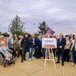 Bewoners, samen met vertegenwoordigers van gemeente Hoeksche Waard, HW Wonen en Zwaluwe Bouw, vieren de feestelijke oplevering van de nieuwe wijk De Veldspring in Strijen. Tijdens de bijeenkomst werd symbolisch een cheque overhandigd als cadeau aan de wijk.