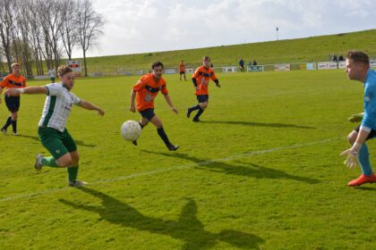 In een spannende één-op-één situatie probeert een speler van Fortuna Be Quick de bal langs de doelman van Simonshaven te schuiven, terwijl verdedigers in de achtervolging zijn. (Foto: Koos Schilperoort)