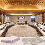 Raadszaal van gemeente Hoeksche Waard met vergaderstukken en een kaart van een ontsluitingsroute.