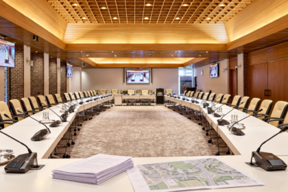 Raadszaal van gemeente Hoeksche Waard met vergaderstukken en een kaart van een ontsluitingsroute.